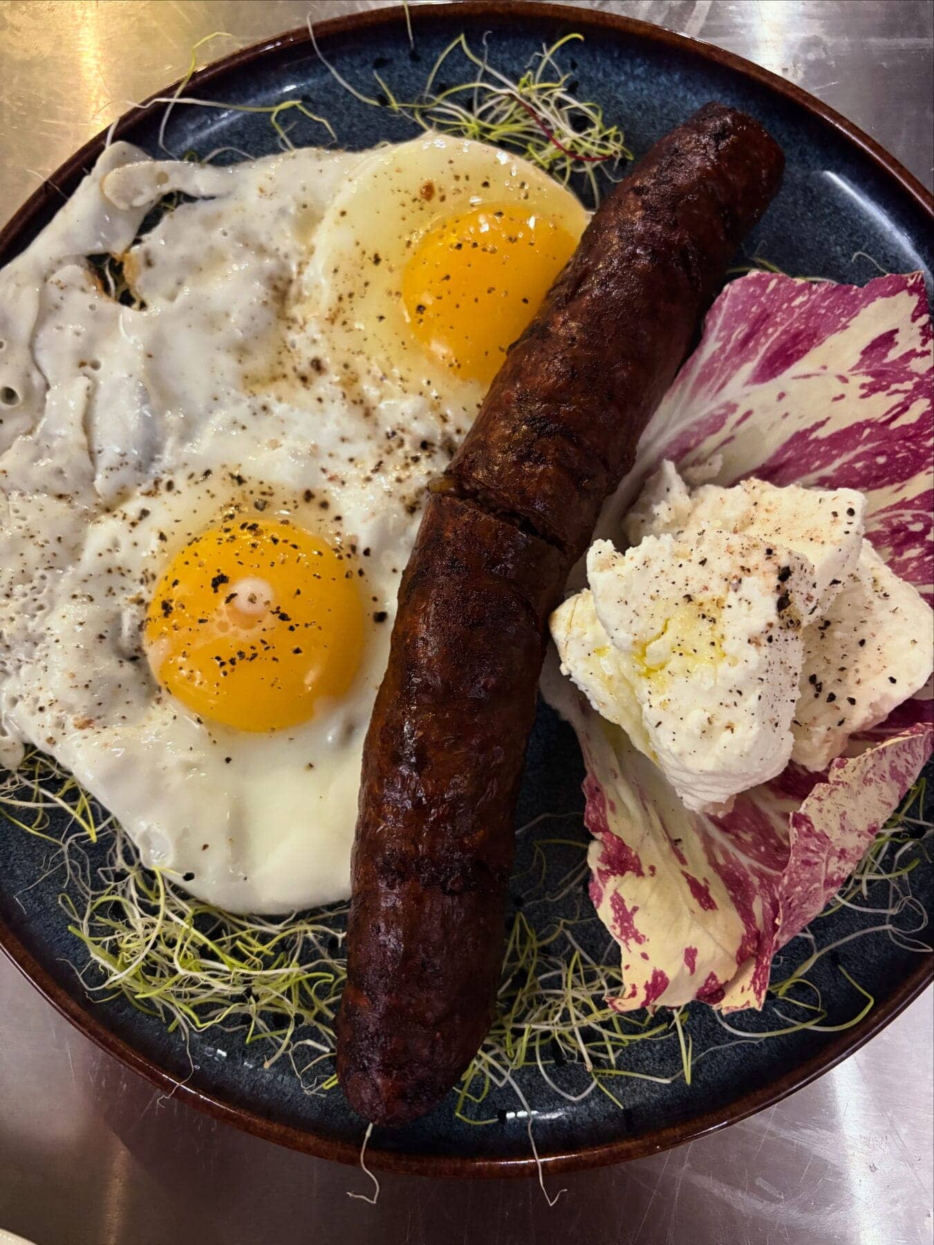 Assiette de figatelli grillé, œuf de ferme et brocciu frais, une manière classique de goûter le fromage corse.