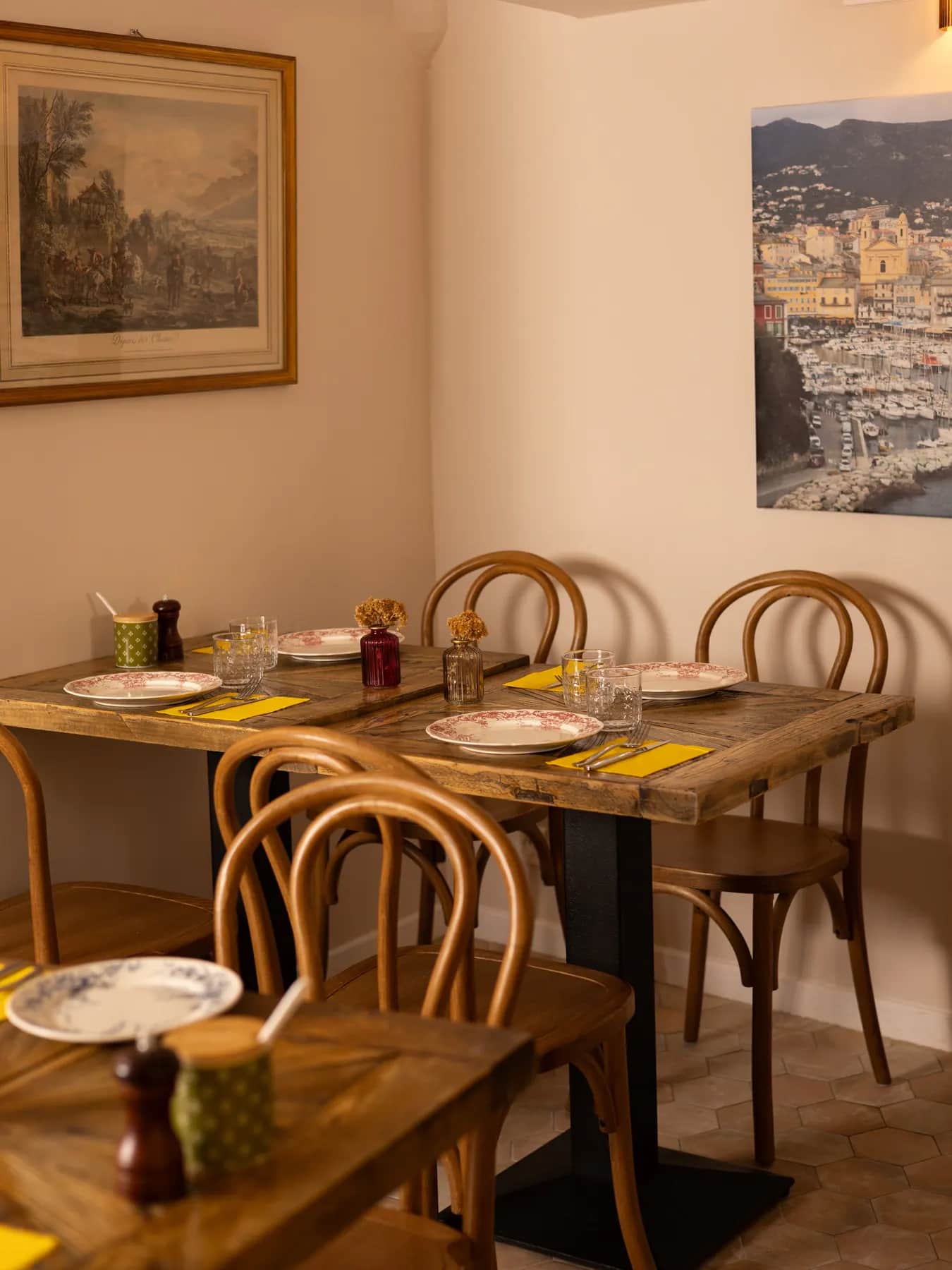 La salle du Bistrot Napoléon à Hyères : tables en bois dressées, chaises bistrot et murs couverts de cadres anciens.