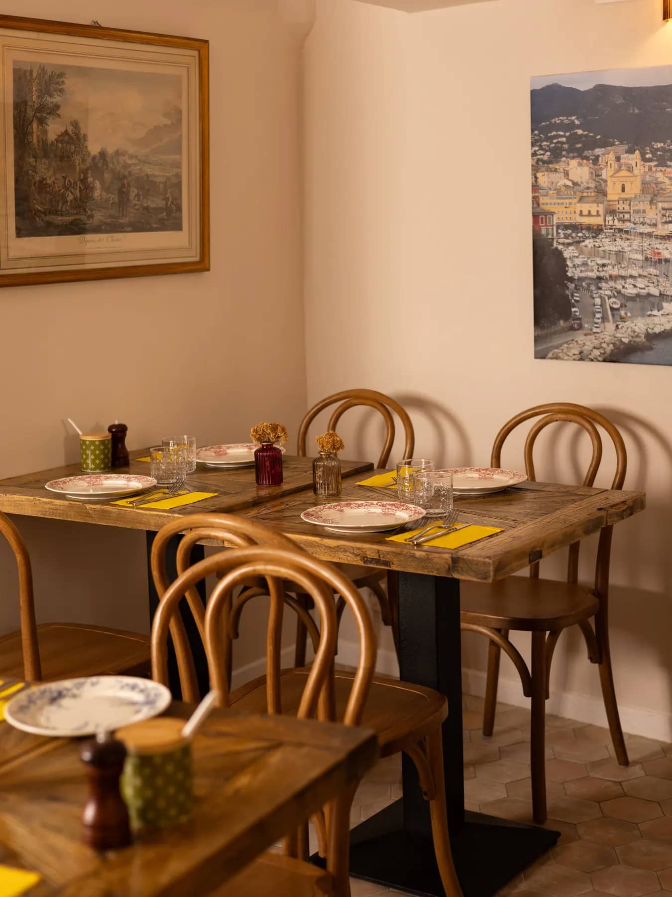 La salle du Bistrot Napoléon à Hyères, au décor éclectique : tables en bois dressées, chaises bistrot et murs de cadres anciens, prête pour un repas de groupe.