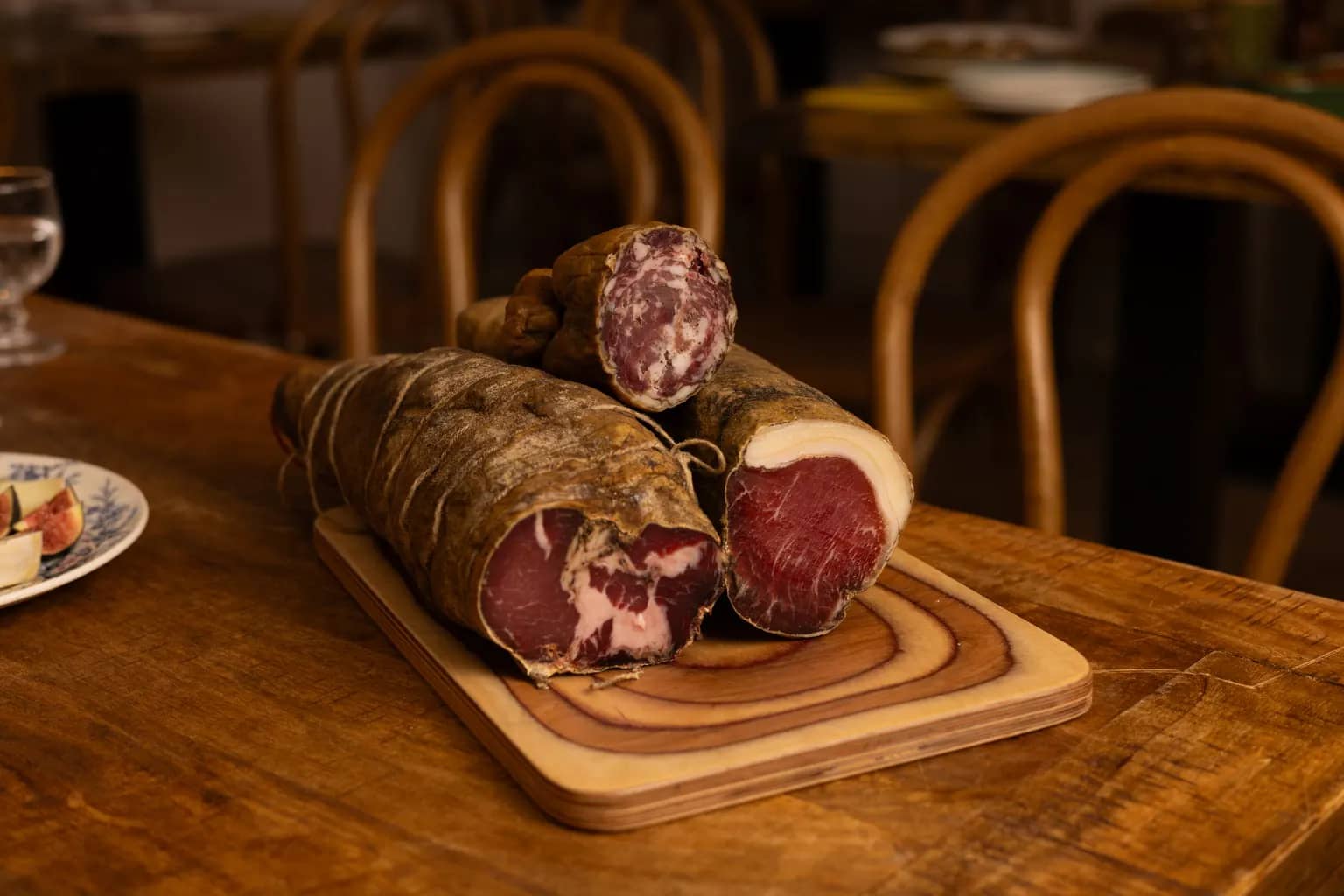 Coppa, lonzu et saucisson corses posés sur une planche en bois au Bistrot Napoléon, prêts à être tranchés pour un plateau à partager.